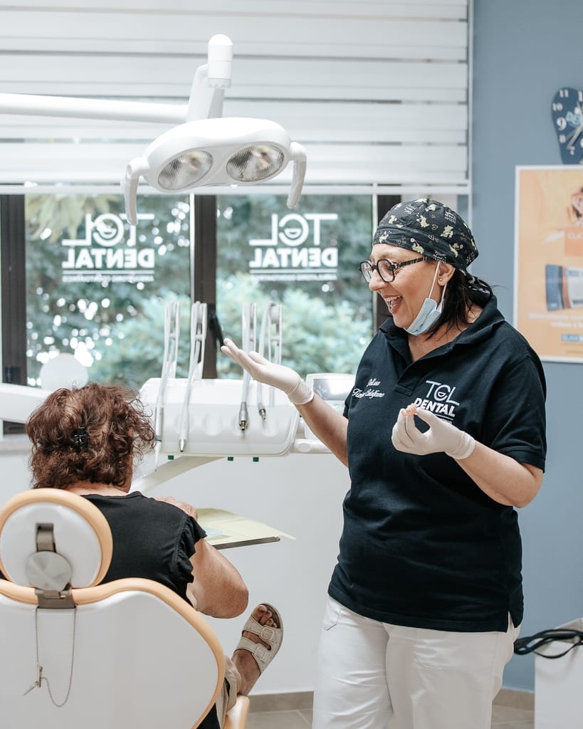 La Dott.ssa Tiziana Catalfamo spiega il piano di cura a una paziente adulta che tiene in mano la cartellina, TCL Dental