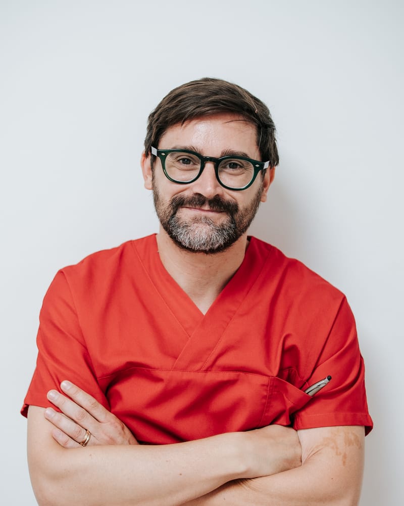 Alessandro Romano, gnatologo, in divisa rossa con le braccia conserte, ritratto su fondo chiaro